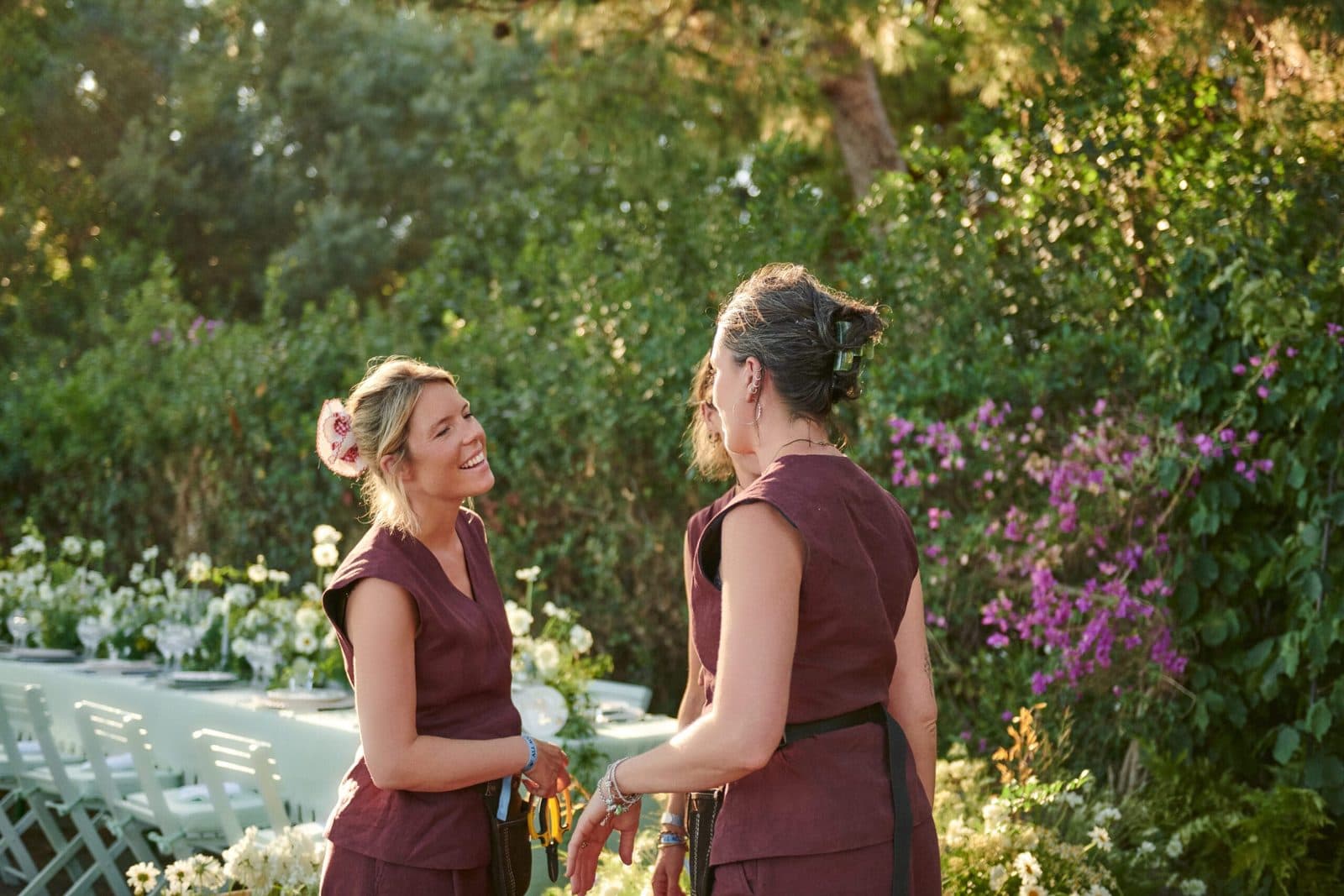 Two members of the LVF team talking on site beside a garden dinner table dressed with white flowers.